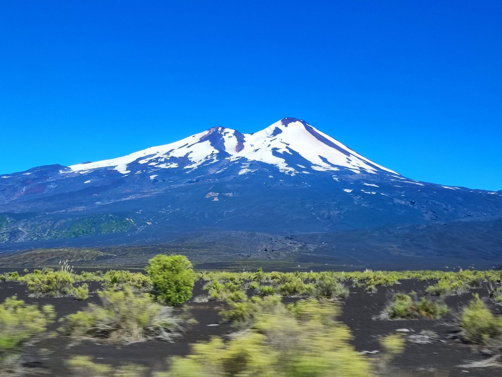 Un volcán nevado sobre un valle verde