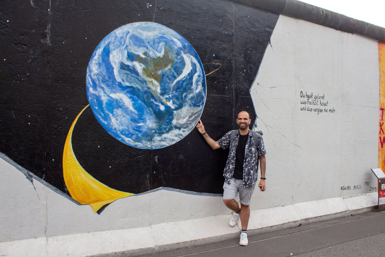 Nicolás neben einem Wandbild der Erde