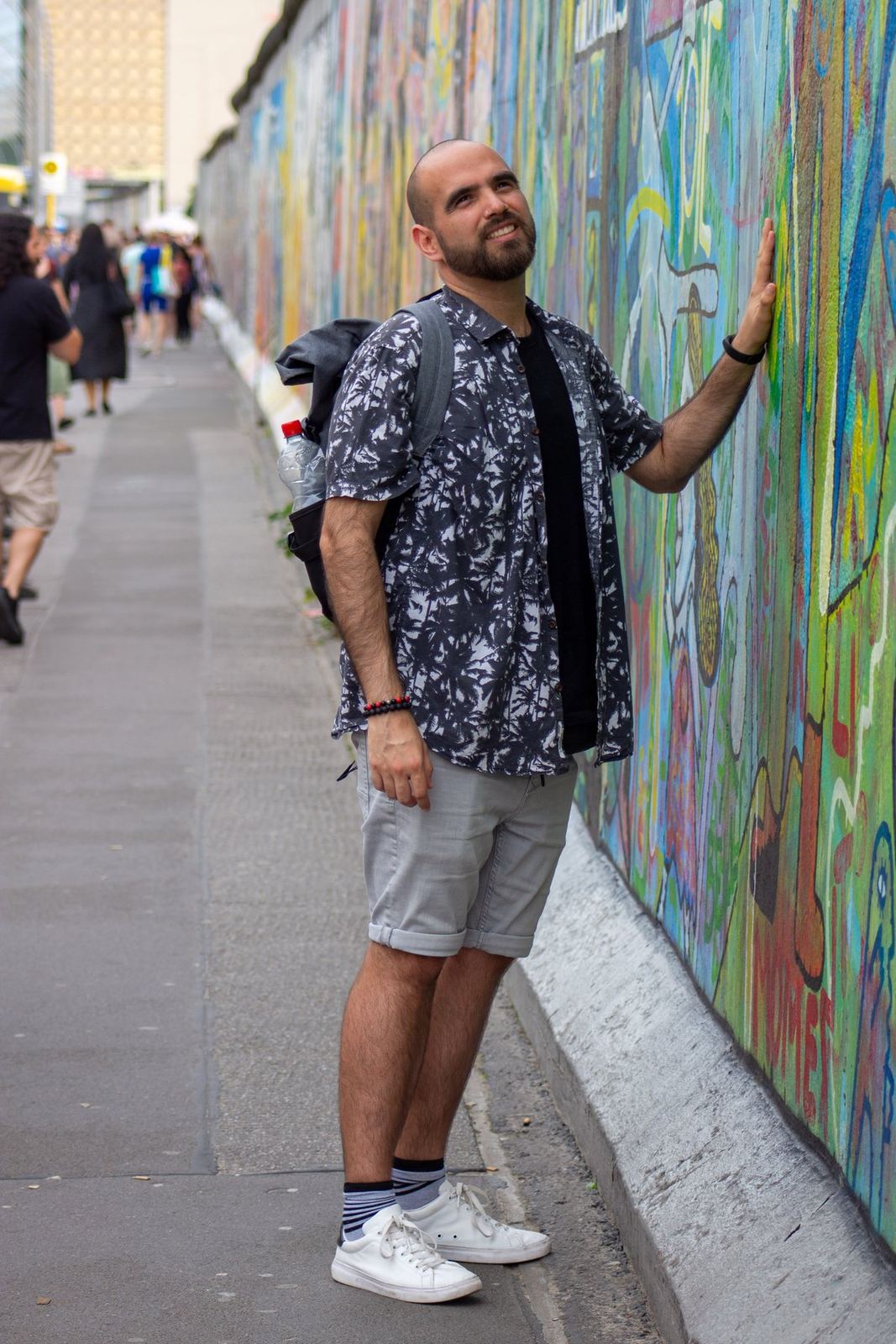 Un viajero posando junto a un largo muro pintado
