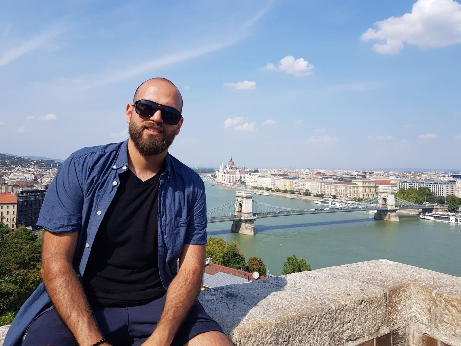 Nicolás sitzt über der Donau, die Stadt hinter ihm