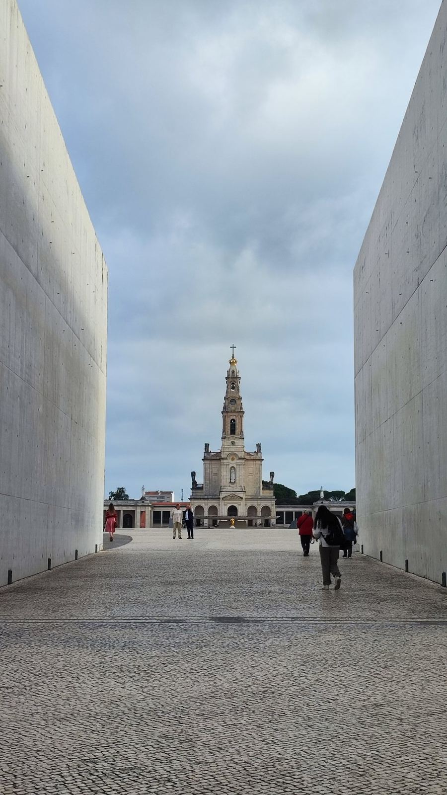 Dos altos muros blancos que enmarcan una torre lejana