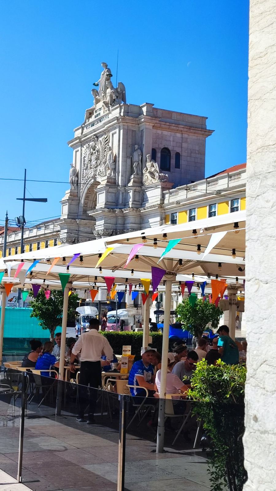 Terrazas de café bajo banderines de colores junto a un arco triunfal