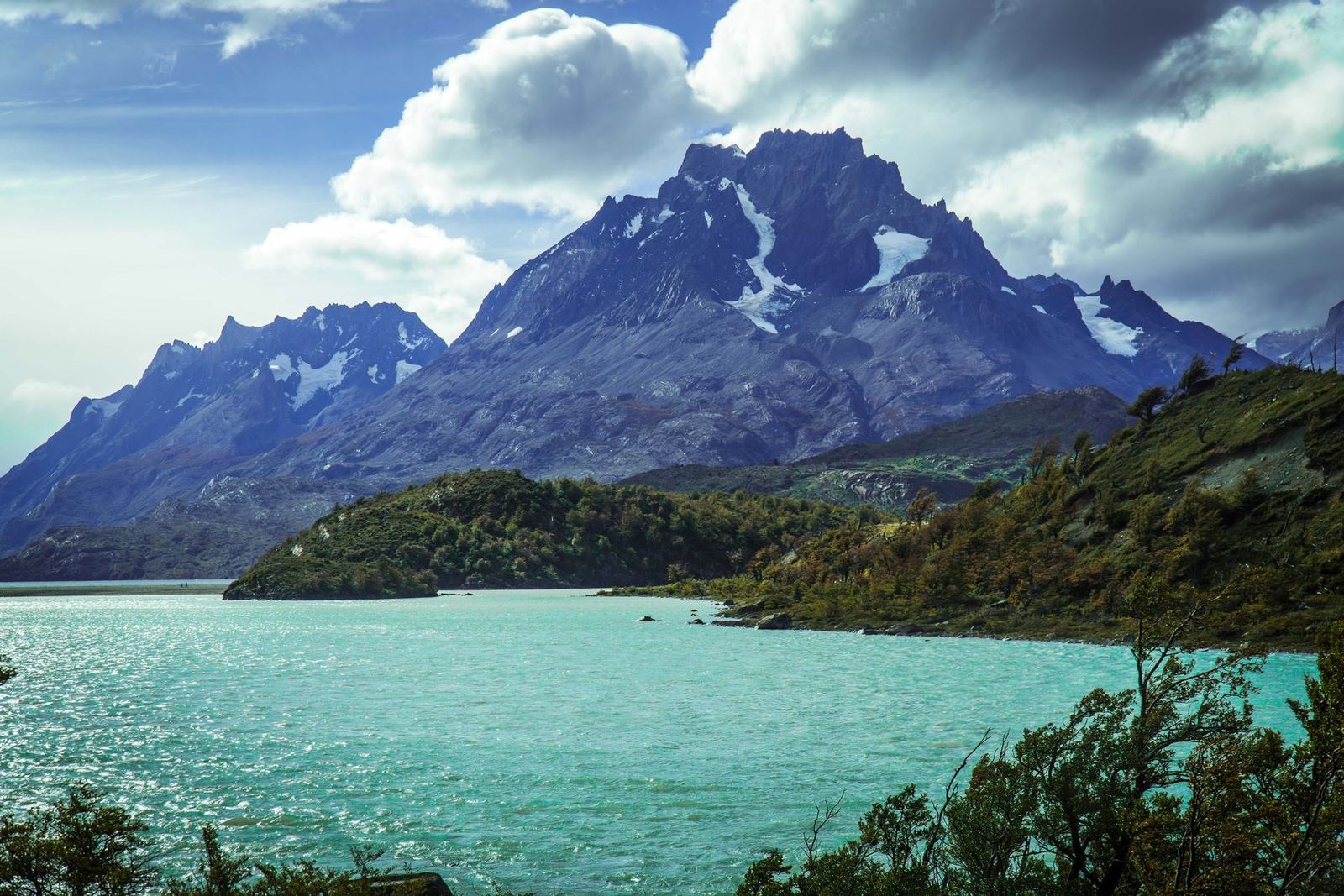 A turquoise lake below a jagged mountain