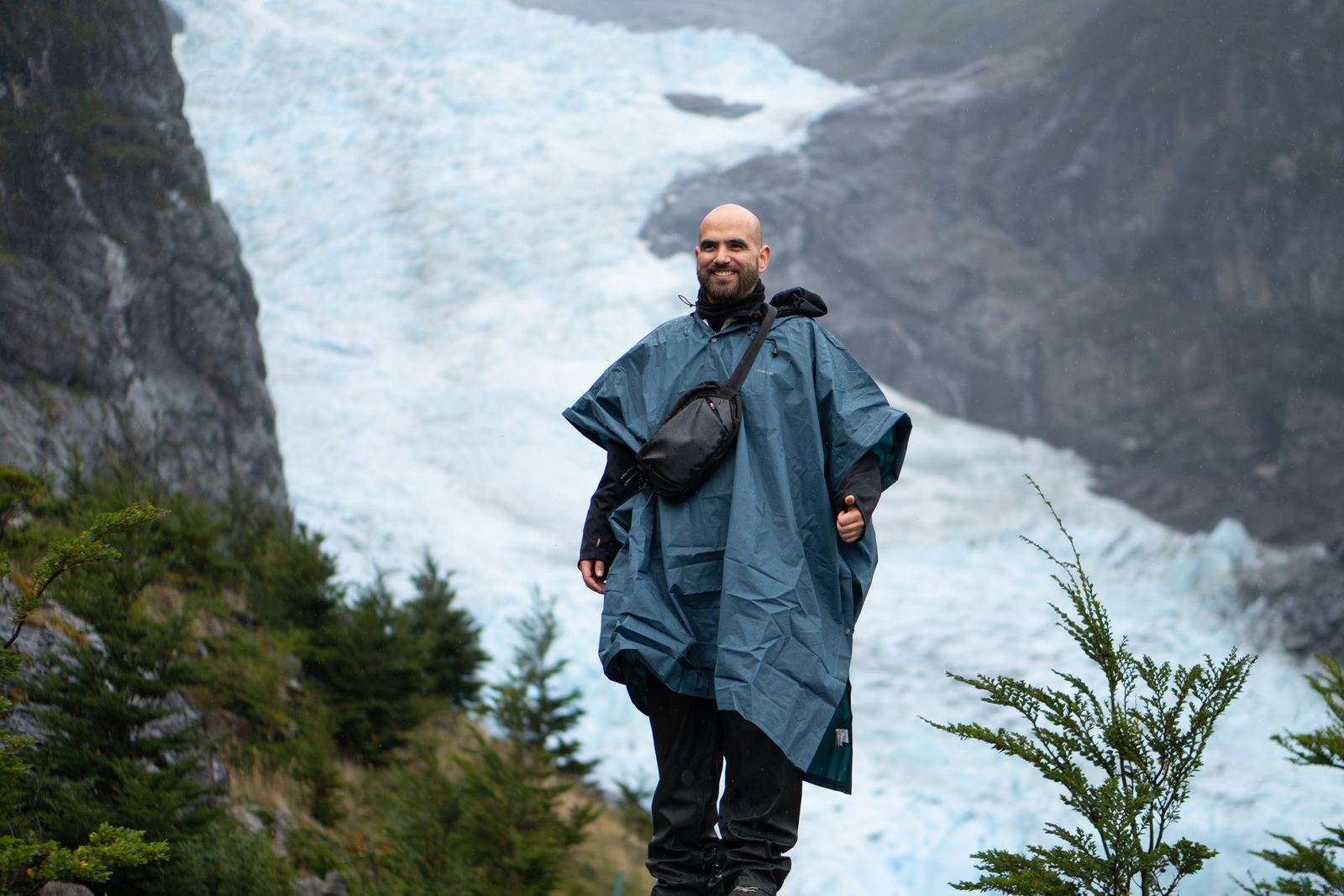 Nicolás im Regenponcho auf einem Felsen vor einem Gletscher