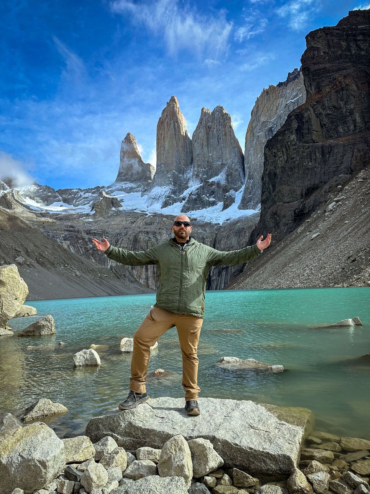 Nicolás mit offenen Armen auf einem Felsen im türkisen See unter Granittürmen