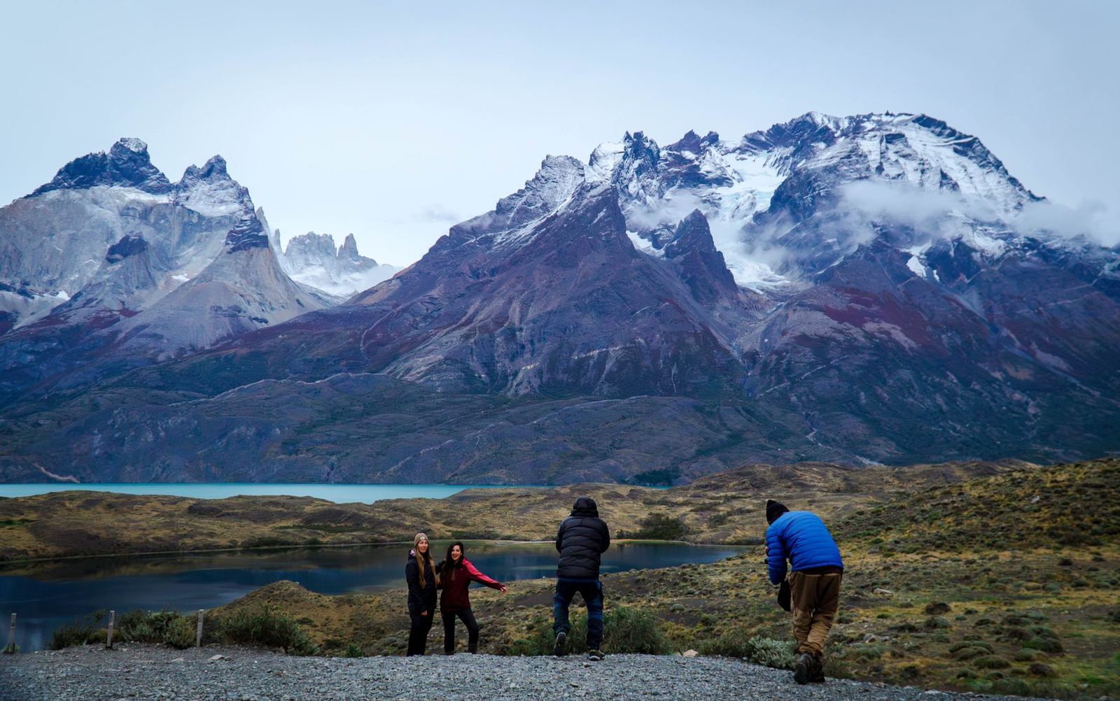 Viajeros fotografiando en un mirador del lago bajo cumbres nevadas