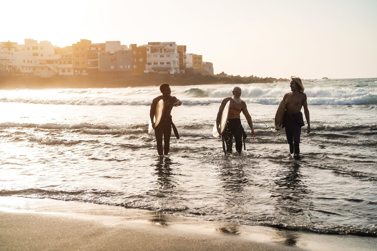 Drei Freunde kommen bei Sonnenuntergang mit ihren Surfbrettern aus dem Meer
